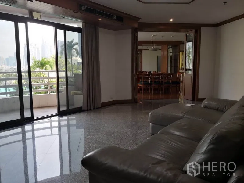 公寓 出租在Khlong Toei, Bangkok - 客厅连接宽阳台，可望城市天际与棕榈树，玻璃门后为餐厅