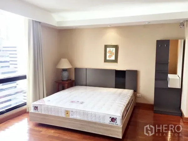 คอนโด ให้เช่าในPathum Wan, Bangkok - ห้องนอนมุม วิวเมืองผ่านหน้าต่าง เตียง โคมไฟ และภาพแขวนผนัง