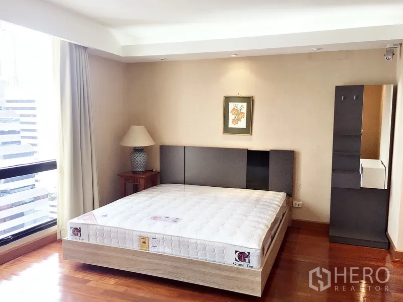 คอนโด ให้เช่าในPathum Wan, Bangkok - ห้องนอนมุม วิวเมืองผ่านหน้าต่าง เตียง โคมไฟ และภาพแขวนผนัง