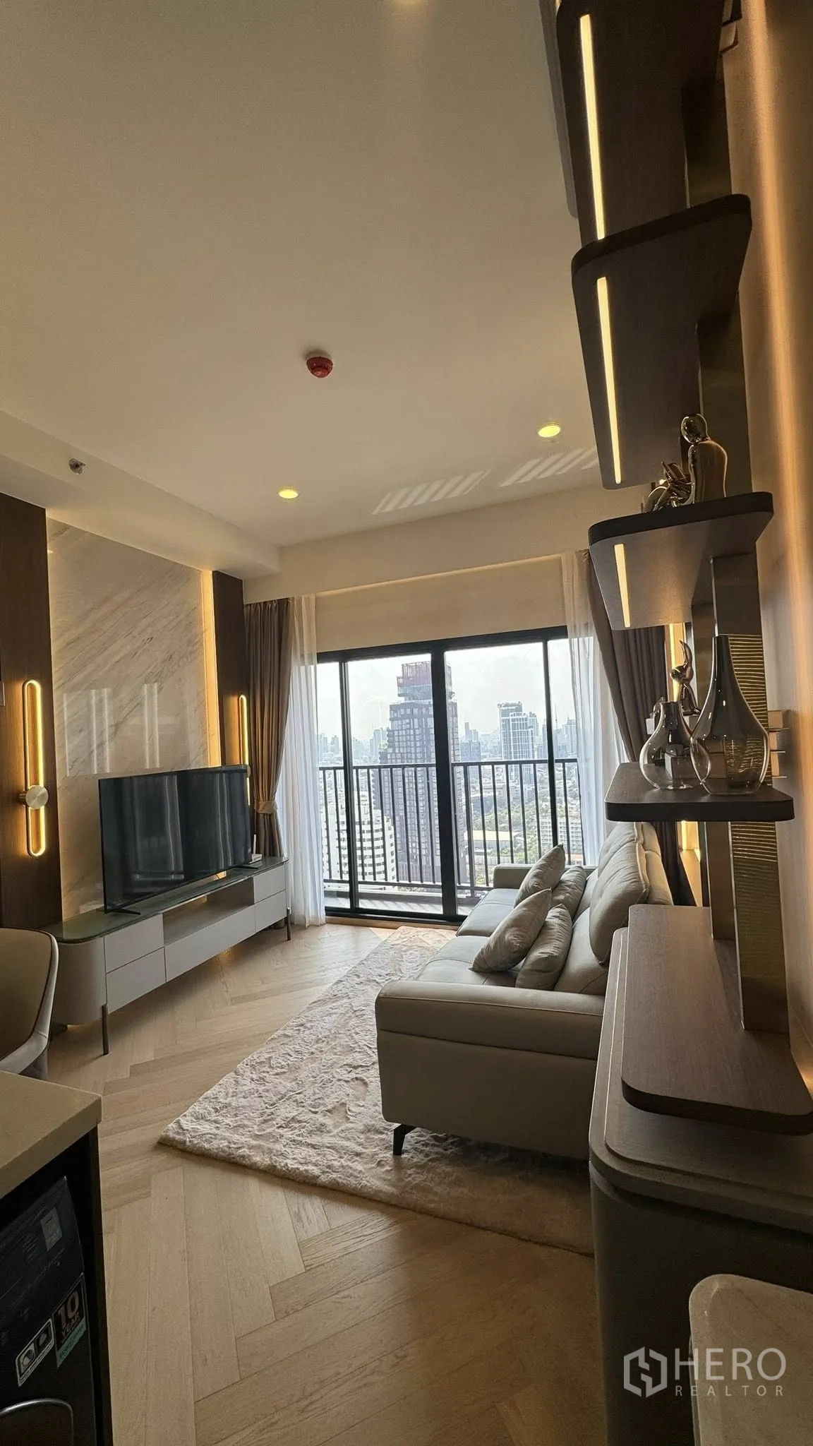 公寓 for rent in Watthana, Bangkok - 采光充足的客厅，配有沙发、电视柜、内置置物架、木地板及可观城市天际线的阳台。