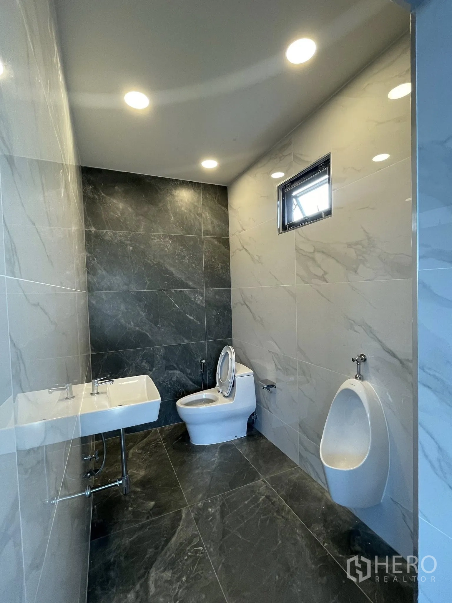Warehouse for rent in Phra Samut Chedi, Samut Prakan - Modern restroom finished with marble-look tiles, toilet, urinal and sink.