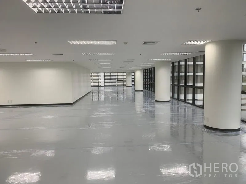 办公空间 出租在Bang Rak, Bangkok - 宽敞办公楼层，圆形立柱、亮面地坪与网格灯顶。