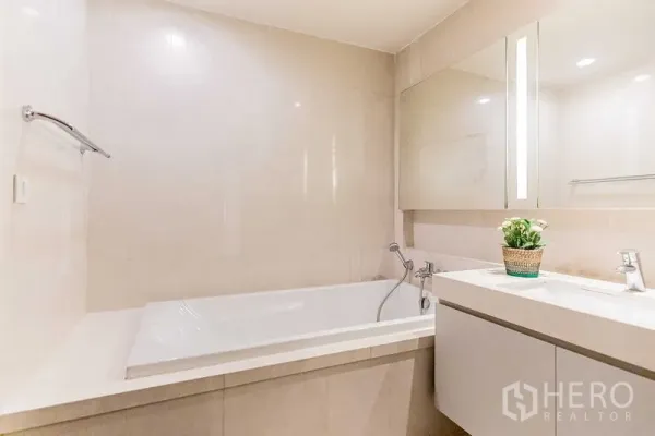 Condominium for rent - Full bathroom view showing built-in tub, illuminated mirror, and sleek vanity.