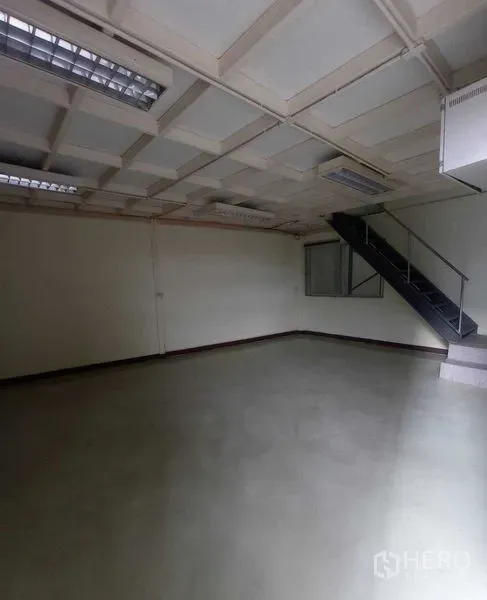Warehouse for rent in Suan Luang, Bangkok - Open-plan office on the ground floor with a stair to mezzanine and fluorescent lighting.