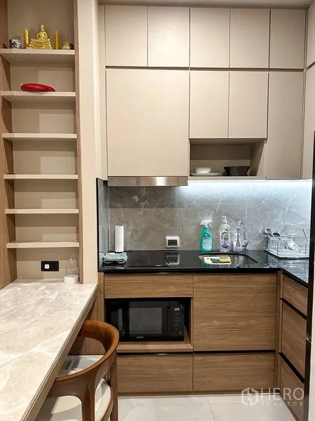 คอนโด ให้เช่าในPathum Wan, Bangkok - ครัวรูปตัวแอลขนาดกะทัดรัด ผนังหิน เคาน์เตอร์ และตู้บิวท์อินพร้อมเครื่องใช้ไฟฟ้า