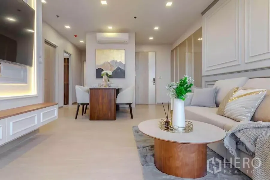 公寓 出租在Huai Khwang, Bangkok - 明亮客厅，沙发、墙面线条、电视背景墙与圆形茶几。