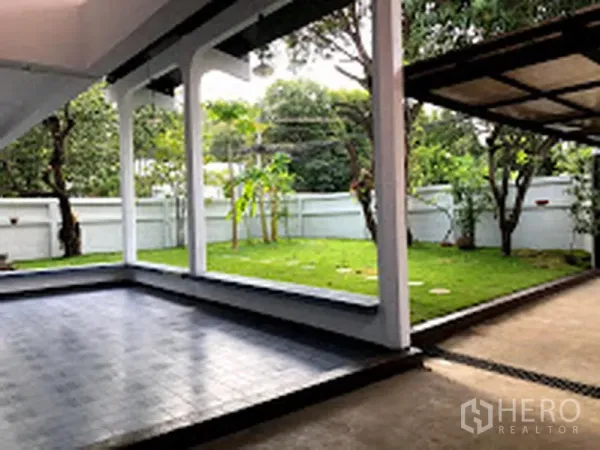 Detached House for rent in Suan Luang, Bangkok - Covered terrace overlooking a private lawn and mature trees in a walled garden.