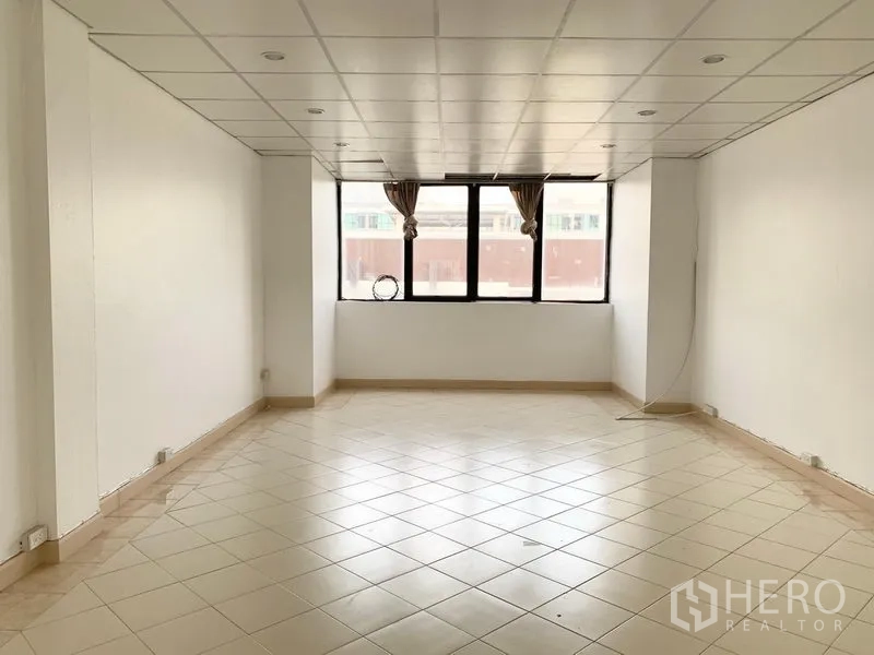 联排别墅 出租在Khlong Toei, Bangkok - 宽敞客厅，白色墙面、瓷砖地面、嵌灯天花和大窗。