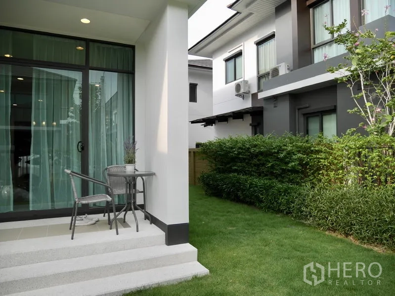 Detached House for rent in Bang Kapi, Bangkok - Small patio with sliding glass doors opening to a lawn beside neighboring modern homes.