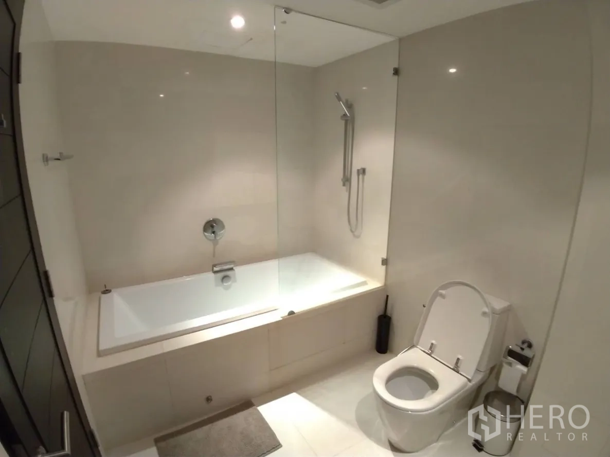 公寓 出租在Watthana, Bangkok - 极简浴室，内置浴缸、玻璃隔断与坐便器，现代Thonglor区域公寓。