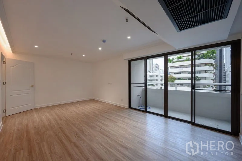 Condominium for sale in Watthana, Bangkok - Large bedroom with wood flooring and full-height sliding doors to the balcony.