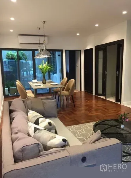 ทาวน์เฮาส์ ให้เช่าในKhlong Toei, Bangkok - โถงนั่งเล่น–รับประทานอาหารแบบโอเพ่นแพลน โซฟา พื้นปาร์เกต์ และประตูกระจกสไลด์สู่ลาน