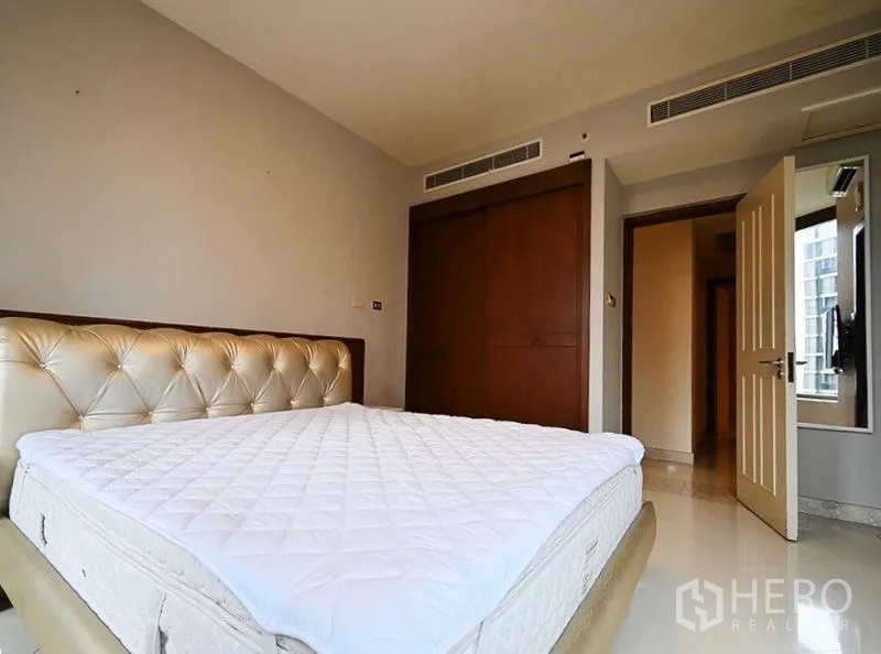 Condominium for rent in Pathum Wan, Bangkok - Second bedroom with tufted headboard, fitted wardrobe, and city-facing window.