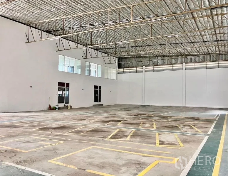 货栈 出租在Prawet, Bangkok - 仓库内部空间宽敞，保温金属屋顶，高度通透，地面划有装卸车位线，带夹层窗。