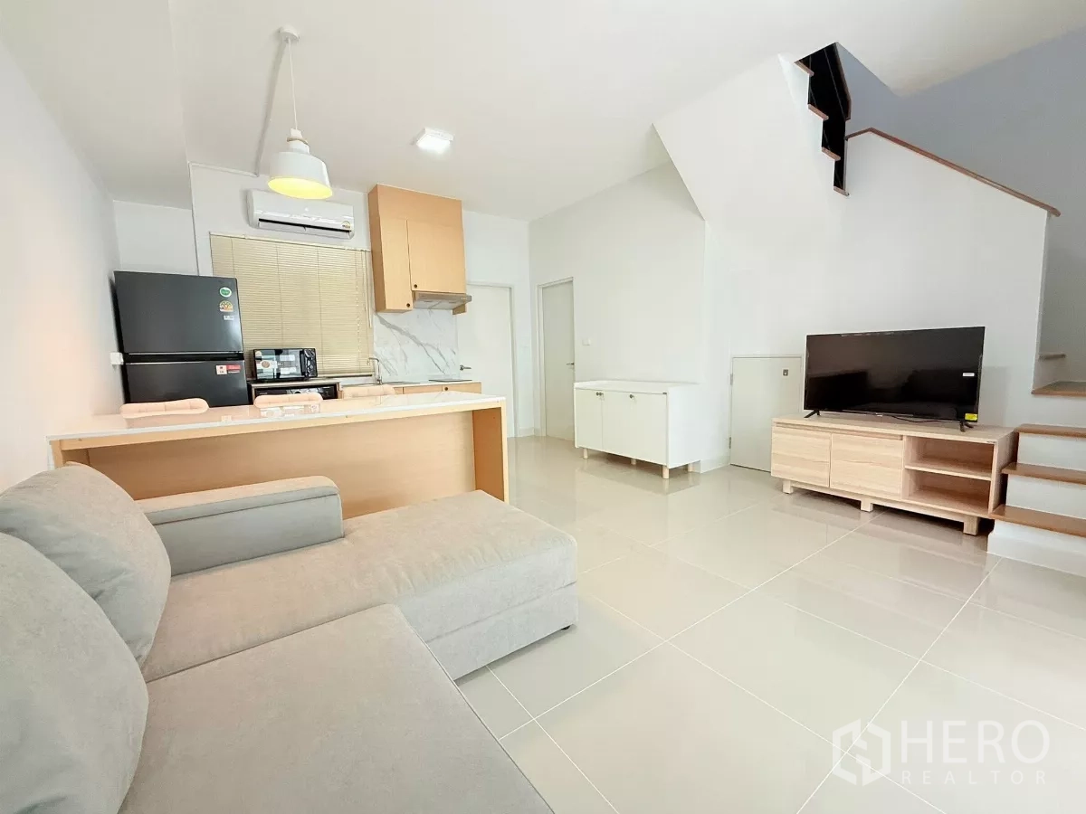 Townhouse for rent in Bang Phli, Samut Prakan - Open-plan living area with TV console, staircase, and kitchen at the rear.