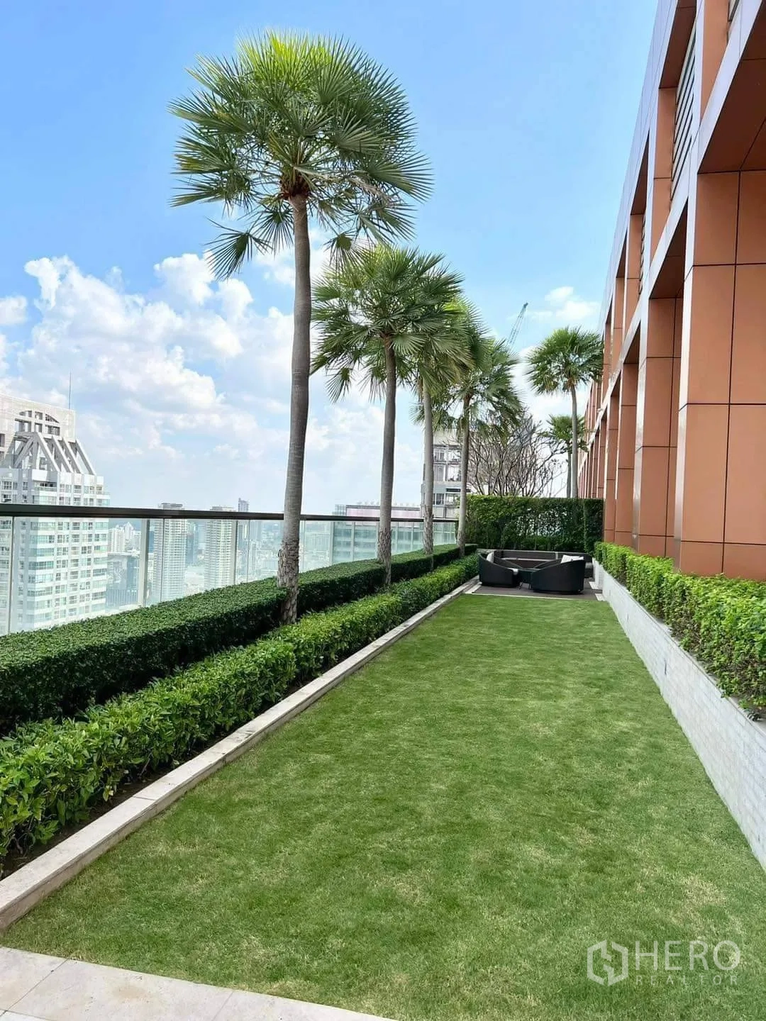 Condominium for rent or sale in Bang Rak, Bangkok - Rooftop garden with palm trees, lawn and seating by a glass railing.