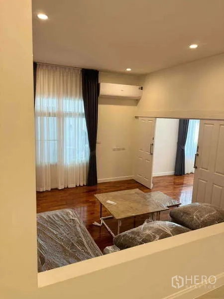 Detached House for rent in Samut Prakan - Cozy lounge with sofa set and coffee table, sheer curtains, and air-conditioner.