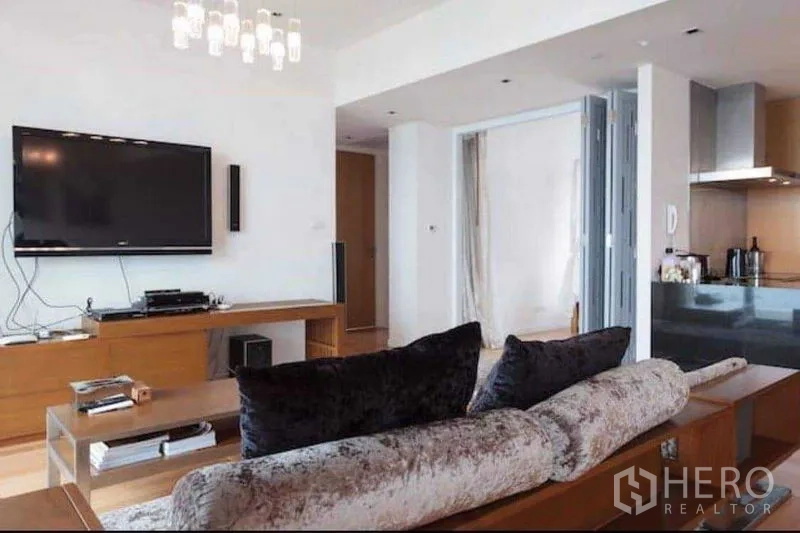 คอนโด ให้เช่าหรือขายในYan Nawa, Bangkok - โถงนั่งเล่นกว้าง โซฟาและทีวีหันสู่ครัวแบบเปิดในคอนโดสว่าง