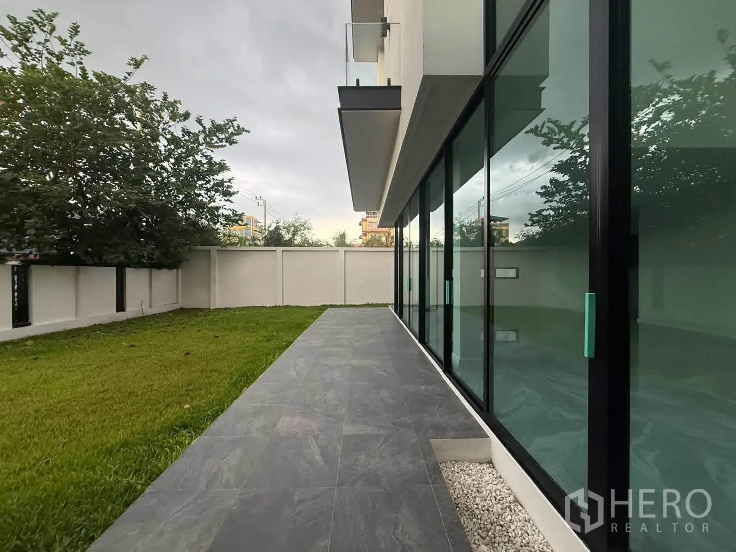 บ้านเดี่ยว for rent in Bang Khen, Bangkok - ชานระเบียงข้างบ้านและสนามหญ้าขนาบด้วยประตูกระจกยาว
