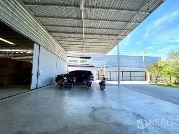 Warehouse for sale in Min Buri, Bangkok - Covered loading bay with wide driveway and parking in front of a modern warehouse.