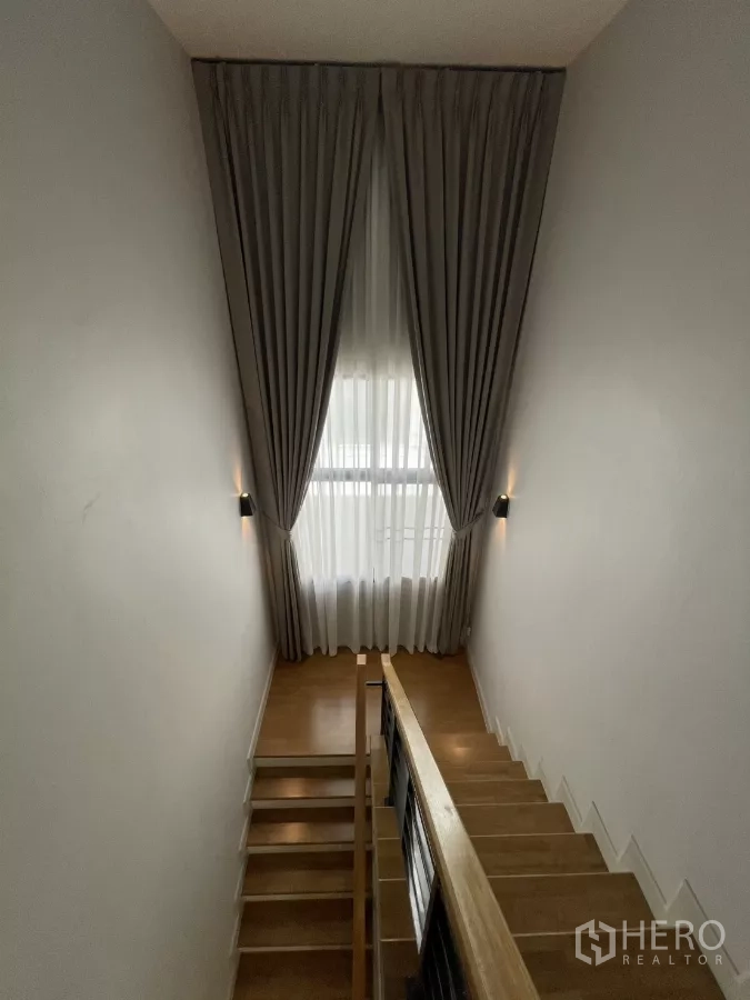 Detached House for rent in Bang Phli, Samut Prakan - Staircase with tall window, full-height drapes, wooden treads and handrail.