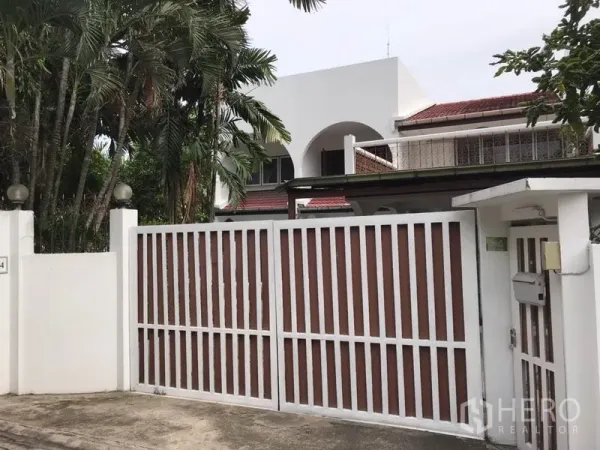 บ้าน ให้เช่าในPhra Khanong, Bangkok - บ้านเดี่ยวสองชั้นสีขาวหลังคากระเบื้องแดง พร้อมรั้วบานใหญ่และต้นปาล์มร่มรื่นในย่านพระโขนง