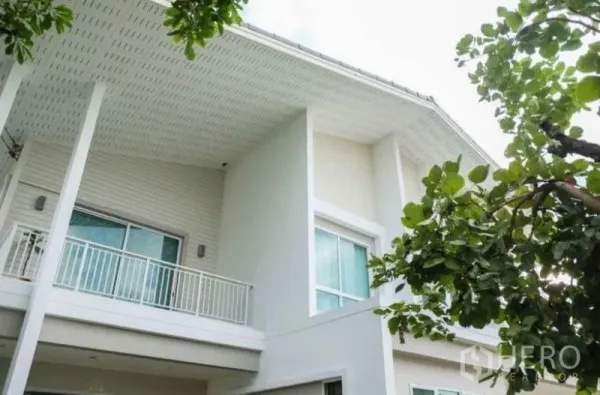 Detached House for rent or sale in Khlong Sam Wa, Bangkok - Upper-floor balcony and wide roof eaves of a contemporary house framed by leafy trees.