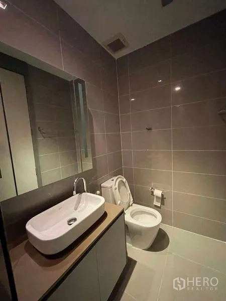 คอนโด ให้เช่าหรือขายในBang Rak, Bangkok - ห้องน้ำที่สองกระเบื้องสีเทาเงา อ่างล้างหน้า กระจก และโถสุขภัณฑ์