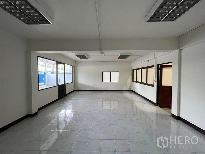 Warehouse for rent in Khlong Toei, Bangkok - Bright tiled office area inside the warehouse with large windows and a sliding glass door.