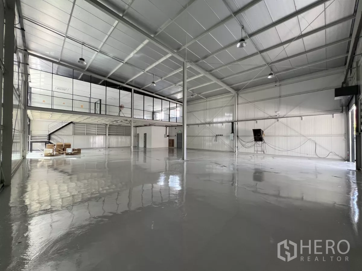 Warehouse for rent in Bang Na, Bangkok - Open warehouse floor with steel structure, bright lighting, and glass-walled mezzanine.