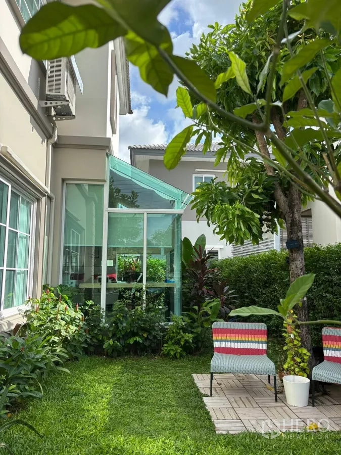 บ้าน ให้เช่าในPrawet, Bangkok - สวนเขียวชอุ่ม มีห้องกระจกอเนกประสงค์ ต้นไม้ และเก้าอี้นั่งหลากสีบนลาน