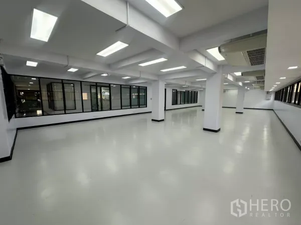 办公空间 出租 - 大面积办公室，多个立柱、玻璃隔墙与均匀分布的顶灯。