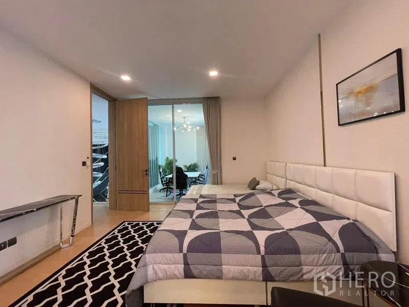 Detached House for rent in Bueng Kum, Bangkok - Spacious bedroom with large bed, wood flooring, console table and sliding glass door to a sunroom or office.