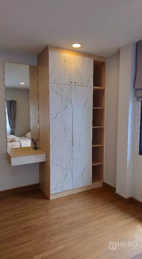 Detached House for rent or sale in Bang Phli, Samut Prakan - Detail of built-in wardrobe with marble-look doors, open shelving and a mirror vanity.