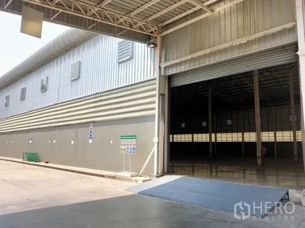 Warehouse for rent in Bang Sue, Bangkok - Industrial warehouse exterior with large roller shutter door and loading ramp for trucks.