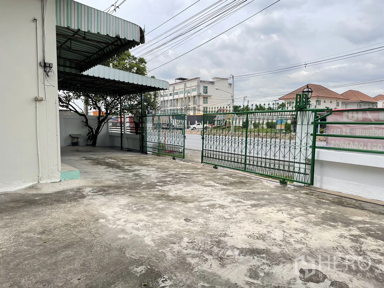 工厂 出租或出售在Pathum Thani - 临路前庭与绿色推拉门，可见道路与周边楼宇。