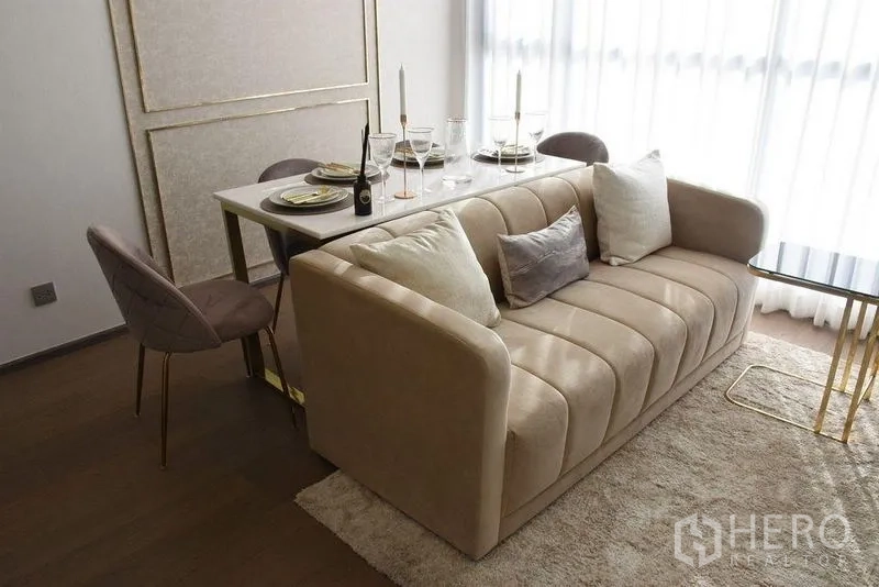 Condominium for rent in Ratchathewi, Bangkok - Dining setup behind a plush sofa with tableware, candles and gold-accent details.