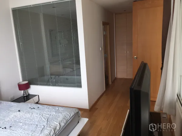 Condominium for rent in Sathon, Bangkok - Master bedroom view toward hallway with built-in wardrobe and glass partition to the bathroom.