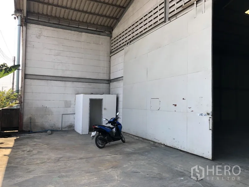 货栈 出租在Khlong Luang, Pathum Thani - 侧面装卸区，金属大门、混凝土场地及一间小型设备房。