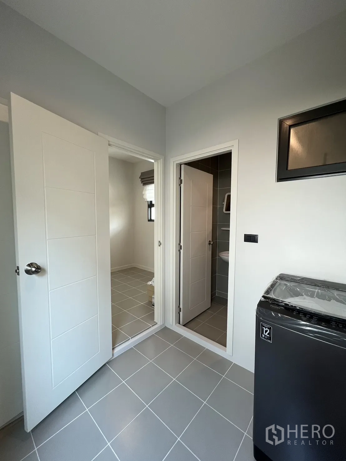 บ้านเดี่ยว for rent in Bang Phli, Samut Prakan - ห้องซักล้างพื้นกระเบื้องสีเทา มีประตูเชื่อมห้องน้ำและห้องเล็ก พร้อมเครื่องซักผ้าแบบฝาบน