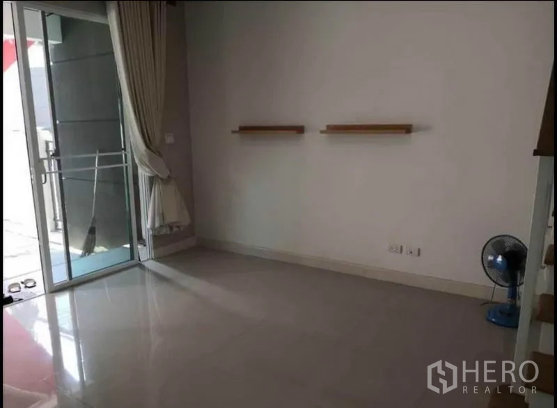 Townhouse for sale in Rat Burana, Bangkok - Bright ground-floor living area with sliding door, tiled floor, and wall shelves.