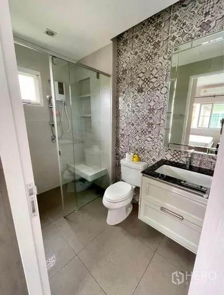 Detached House for rent in Bang Phli, Samut Prakan - Modern bathroom with patterned feature wall, glass shower, vanity and toilet.