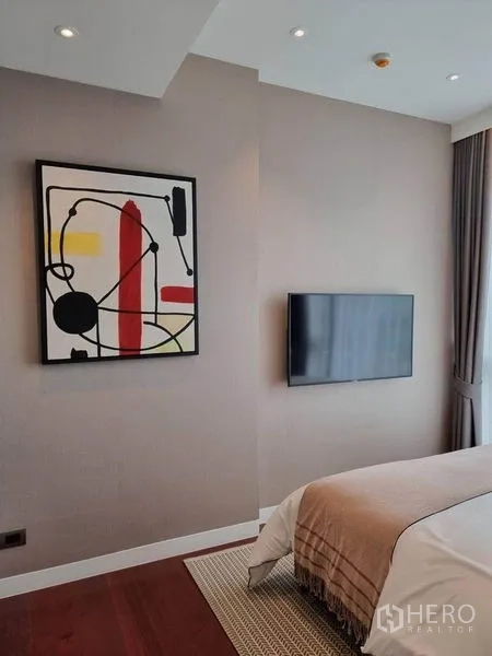 公寓 出租在Watthana, Bangkok - 卧室配墙挂电视与抽象画，大窗搭配窗帘，风格现代。