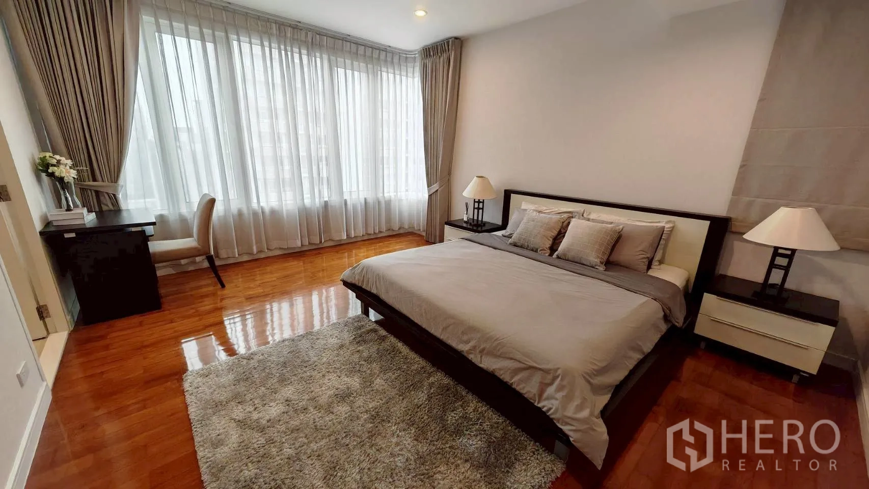 Condominium for rent in Khlong Toei, Bangkok - Spacious master bedroom with king bed, desk and floor-to-ceiling windows.