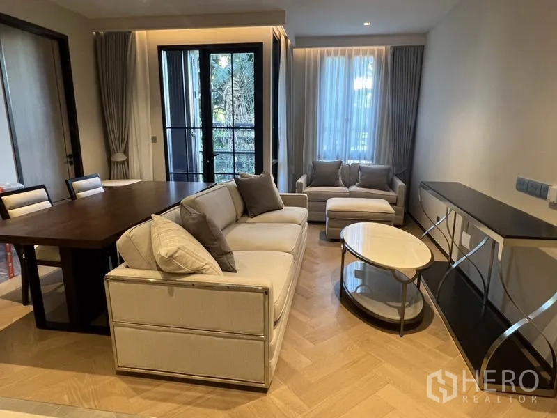 คอนโด ให้เช่าในKhlong Toei, Bangkok - โซนพักผ่อนพร้อมโซฟา โต๊ะกลางกลม และประตูระเบียงมองเห็นต้นไม้