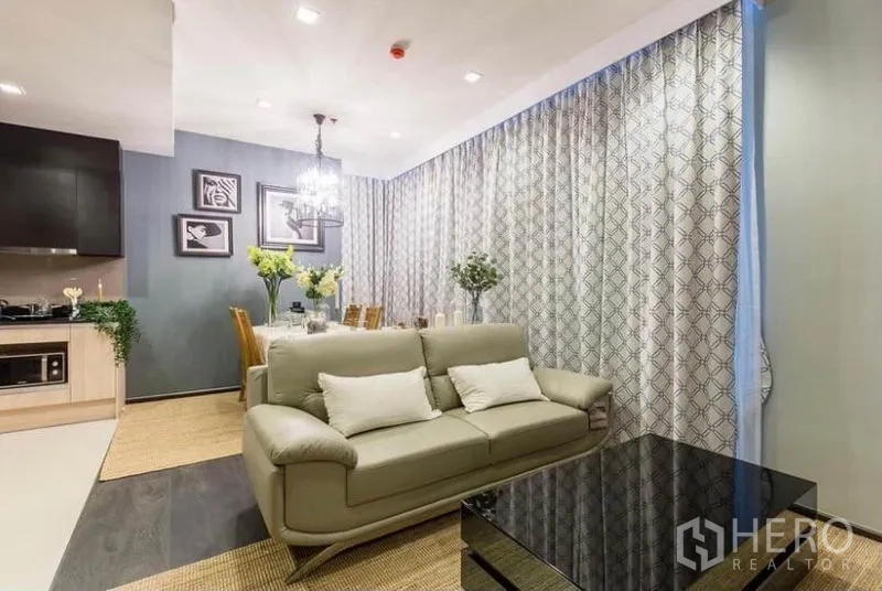 คอนโด ให้เช่าหรือขายในWatthana, Bangkok - ห้องนั่งเล่นโอเพนแพลนพร้อมโซฟาหนัง โต๊ะกลางกระจก และโคมไฟแชนเดอเลียร์ ใกล้มุมทานข้าวและครัว