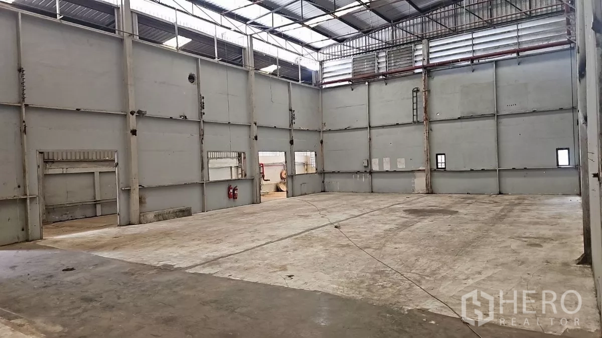 工厂 出租在Pak Kret, Nonthaburi - 开阔生产区，墙体高大带保温层，屋面采光带与壁挂灭火器。