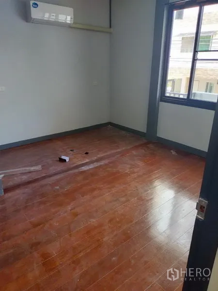 Detached House for rent in Watthana, Bangkok - Bright bedroom with wood floors, large window and wall-mounted air conditioner.