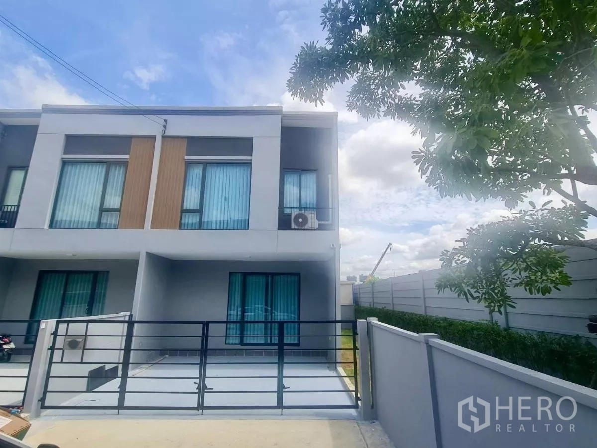 Townhouse for rent in Bang Phli, Samut Prakan - Modern two-storey corner townhouse with gated parking and blue glass windows.