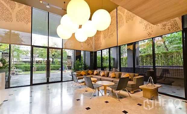 Condominium for rent or sale in Watthana, Bangkok - Bright double-height lobby lounge with floor-to-ceiling windows, pendant lights and garden views.